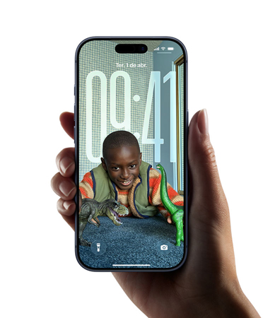 Uma mão segurando um iPhone que mostra a tela com o novo design de Liquid Glass, que faz as horas se adaptarem dinamicamente à imagem da tela bloqueada.