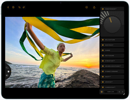 iPad Air, Vorderseite, Bearbeitung eines Fotos einer Person, die vor dem Hintergrund eines Sonnenuntergangs am Meer ein grünes und ein gelbes Tuch hält, mit Bearbeitungswerkzeugen auf der rechten Seite