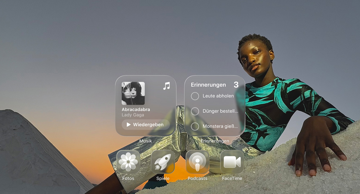 Liquid Glass Display mit transparenten App Symbolen für Apple Music, Erinnerungen, Fotos, Spiele, Podcasts und FaceTime, die das Hintergrundbild reflektieren