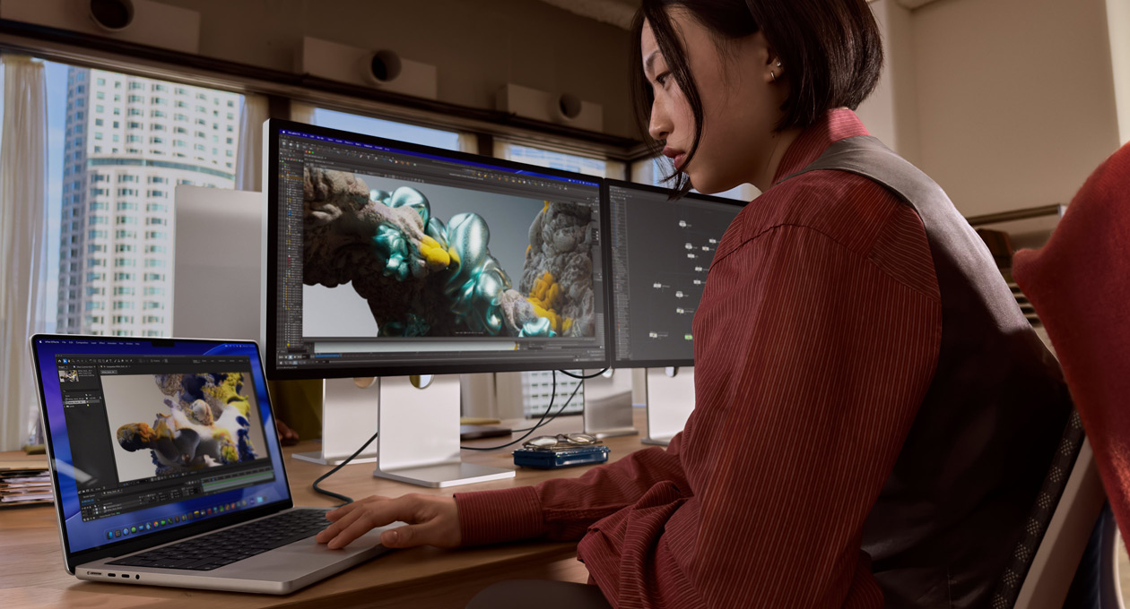 Pessoa a trabalhar num escritório com um portátil MacBook ligado a um Studio Display XDR por uma porta Thunderbolt 5
