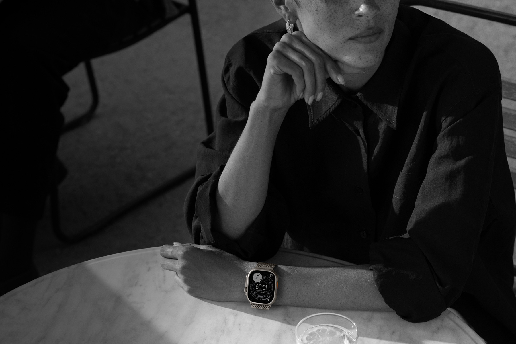 Une personne dînant en terrasse porte une Apple Watch Ultra 3