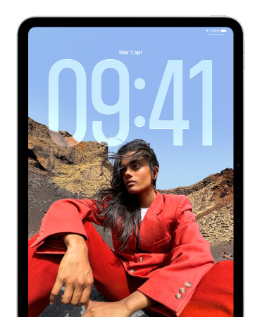 Un iPad che mostra la schermata di blocco con i grandi numeri dell’ora dietro all’immagine di una persona seduta