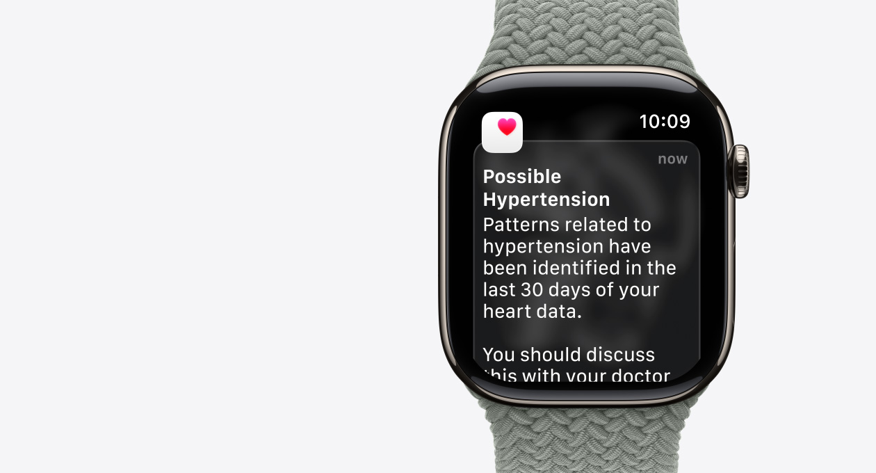 Apple Watch Series 11, natural color, titanium case, possible hypertension notification, pink heart in white box, right side exterior, Digital Crown, band, green gray Braided Solo Loop