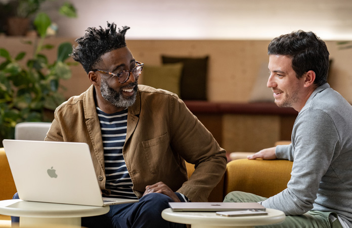 MacBook aperto su un tavolo davanti a una persona che sorride