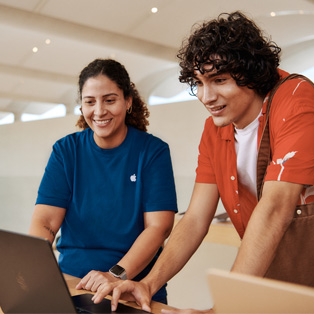Bir müşteri ve yanındaki Apple Store çalışanı birlikte bir MacBook’u kullanıyor.