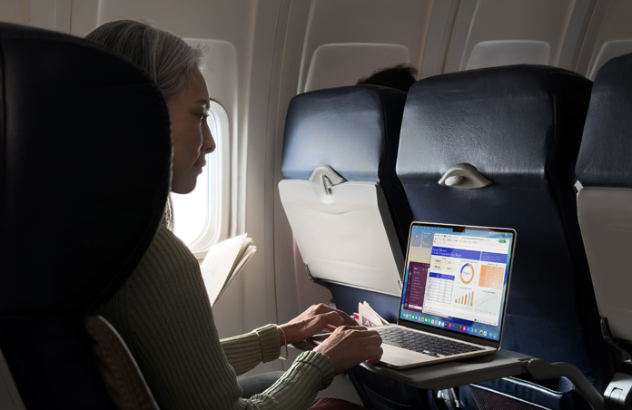 飛行機の座席でMacBook Airを使って作業している人物
