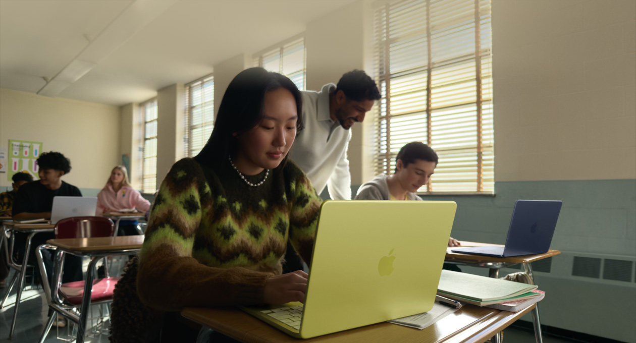 Une personne étudiant utilise un MacBook Neo, couleur jaune agrume, débranché, dans une salle de classe